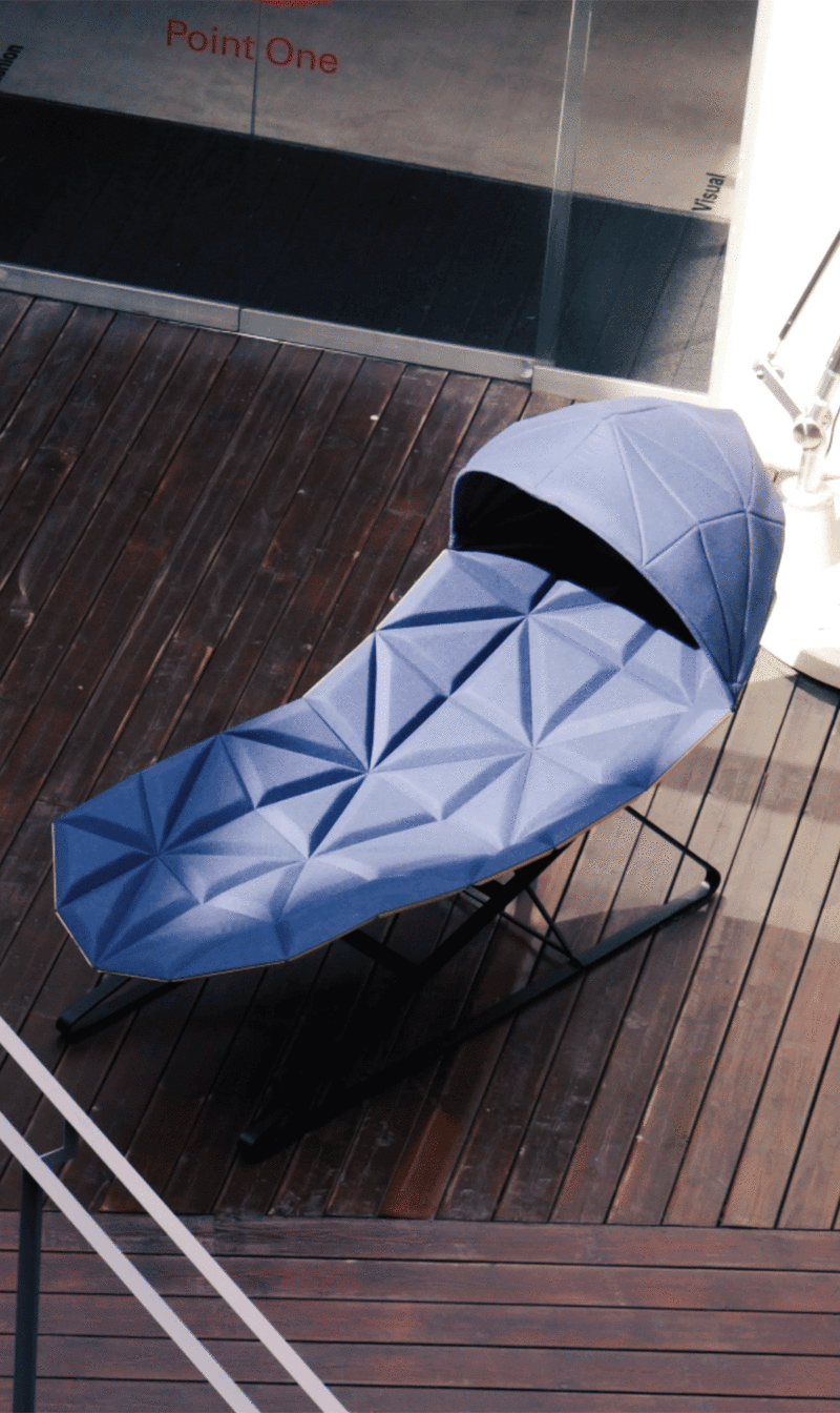 Diván acolchado en tela azul con una gran capota sobre una terraza