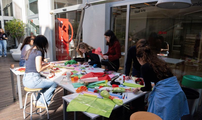 Un grupo de estudiantes diseñando felicitaciones para añadir a las Rosas de Sant Jordi en el patio de entrada del IED Barcelona