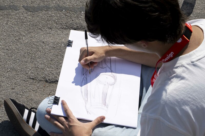 Primer plano de un boceto de transporte con un chico dibujando un coche