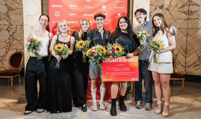 Siete estudiantes posando con ramos de flores en un photocall de premiación