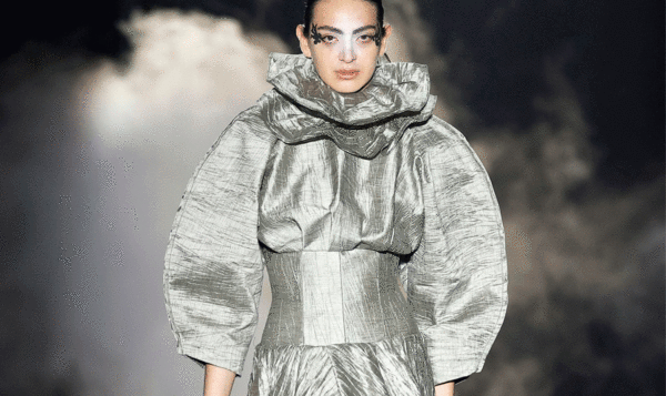 Modelo con un vestido plateado gris brillante de cuello alto con volantes y mangas anchas abombadas de Guillermo Justicia, alumnus del IED Barcelona, en la 080 Barcelona Fashion