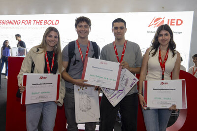 Los ganadores, dos chicas y dos chicos, del III Sketching marathon frente al estand del IED del Salón Automobile sujetando los diplomas acreditativos de su victoria