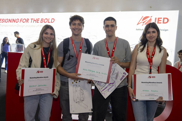 Los ganadores, dos chicas y dos chicos, del III Sketching marathon frente al estand del IED del Salón Automobile sujetando los diplomas acreditativos de su victoria