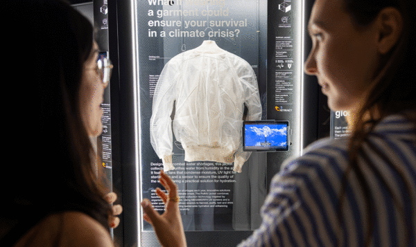Dos mujeres admirando una chaqueta blanca exhibida en una vitrina en el centro de la imagen