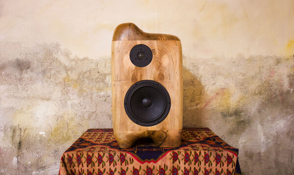 Altavoz de madera colocado sobre una mesa tapada con una manta de cuadros