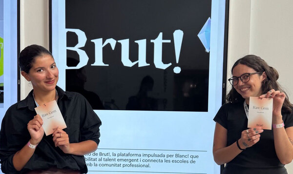 Dos chicas sosteniendo un programa de papel delante del cartel de un festival de diseño