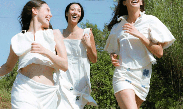 Tres chicas vestidas de blanco corriendo en un jardín en un día soleado