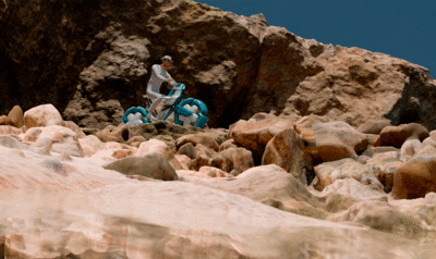 Motociclista sobre una moto anfibia en un paisaje de playa y rocas